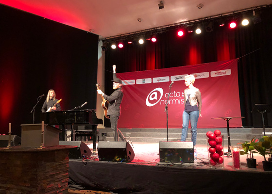 Tre musikere på scenen i Salem menighet med Acta-banner hengende bak