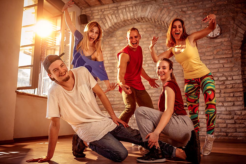 Moderne dansegruppe med ungdommer poserer i gammel bygning, mens solen skinner gjennom ruten